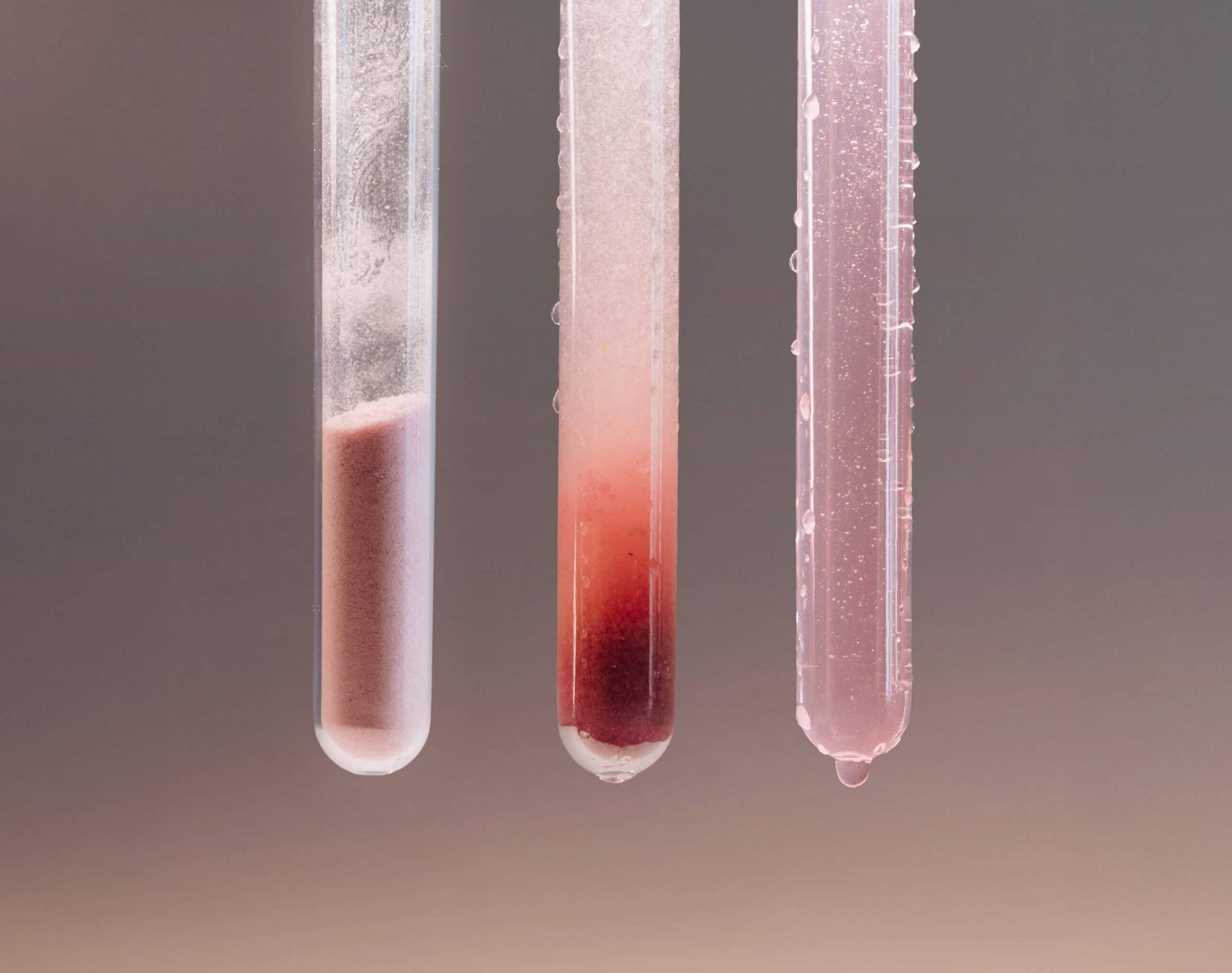 Three test tubes with a gradient of red liquid against a gradient background